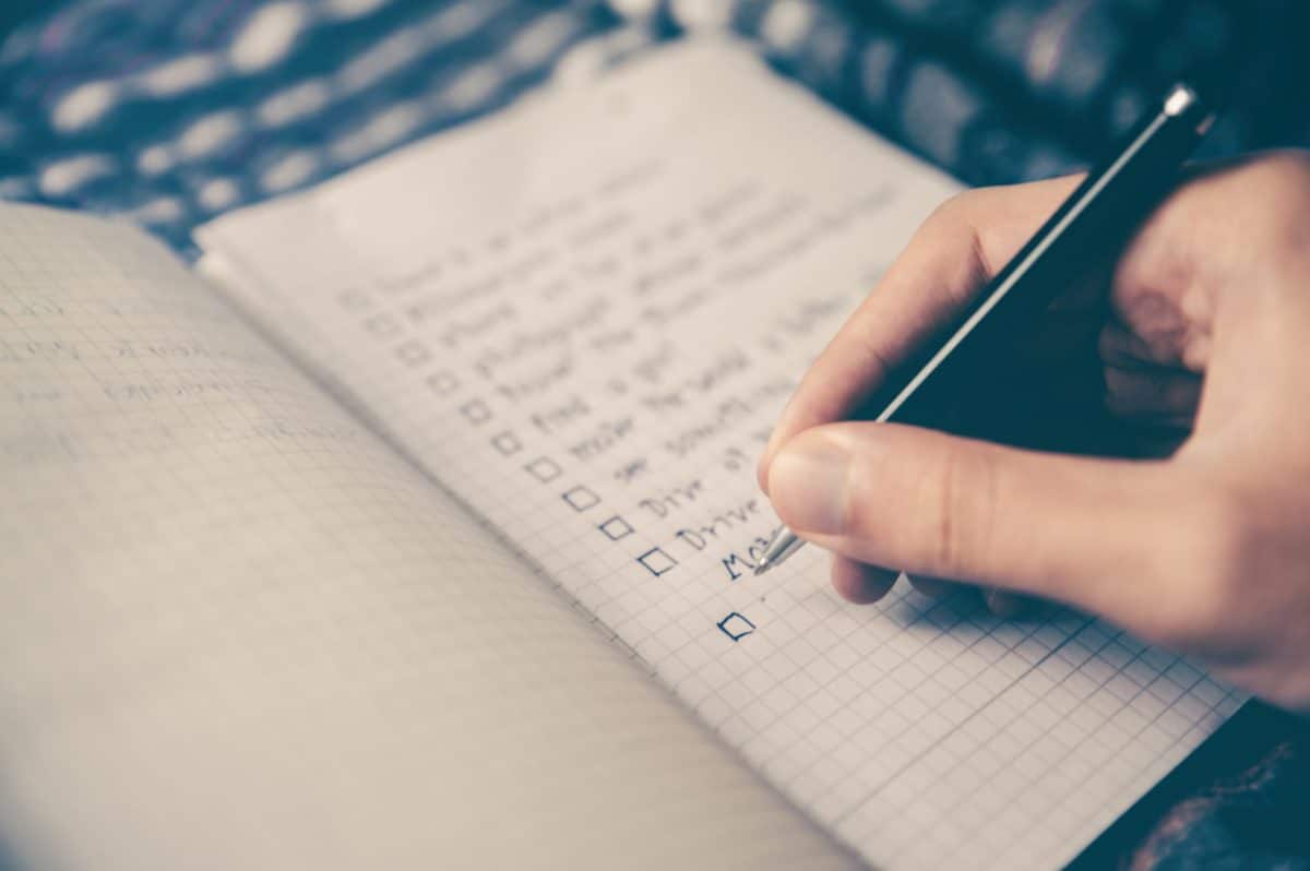 woman's hand writing checklist of what you should include in your will